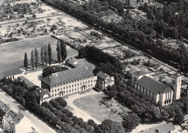Das Foto zeigt eine Luftaufnahme der wiederaufgebauten Ostschule. Rechts ist die Kirche St. Bonifatius zu sehen.