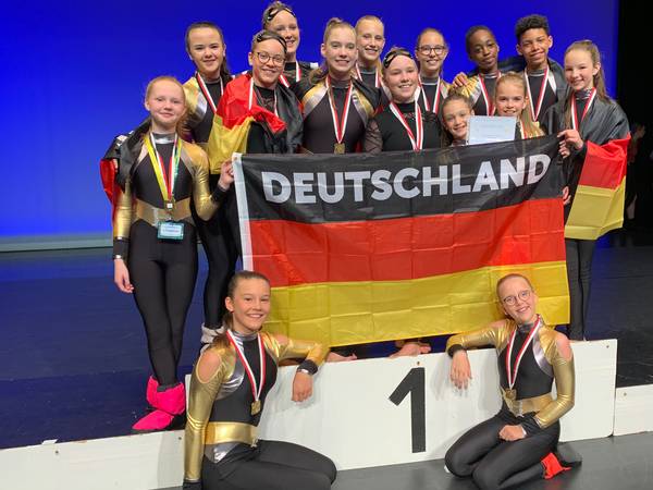 Tänzerinnen und Tänzer der Musikschule Düren mit ihren Medaillen von den Welt- und den Europameisterschaften und einer Deutschlandfahne.