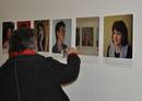 Das Foto zeigt ein paar der 99 ausgestellten Frauenporträts und eine Museumsbesucherin, die sich vor dem Spiegel inmitten der Bilder selbst fotografiert.